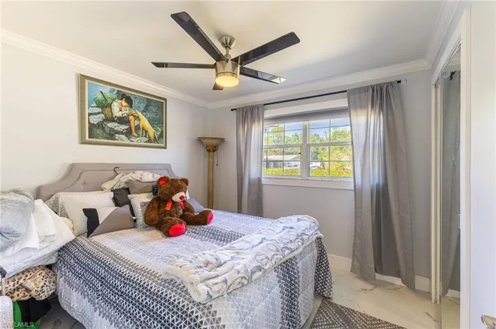 Bedroom featuring marble finish floor, crown molding, baseboards, and ceiling fan