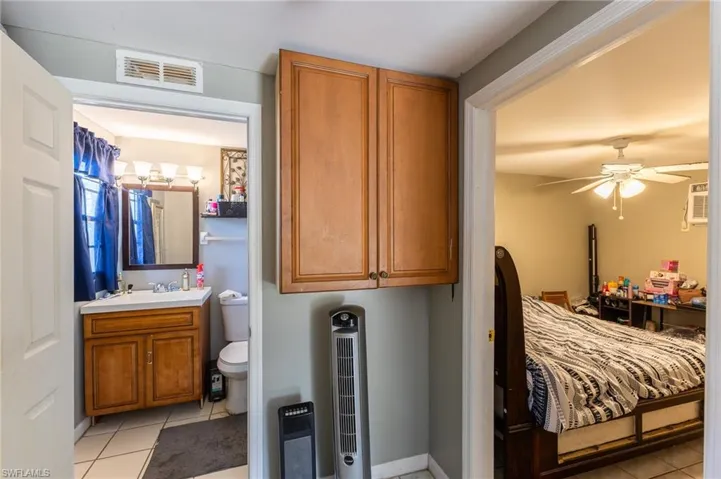 Bedroom featuring heating unit, light tile patterned floors, and visible vents