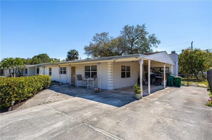 Ranch-style house featuring a carport, concrete driveway, and fence