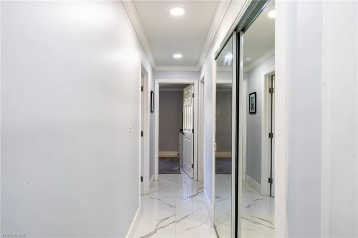 Hall featuring baseboards, marble finish floor, recessed lighting, and crown molding