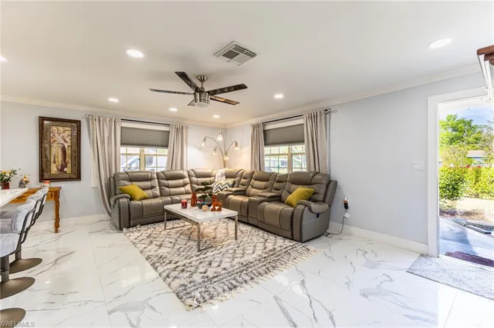 Living area with recessed lighting, baseboards, visible vents, and ornamental molding