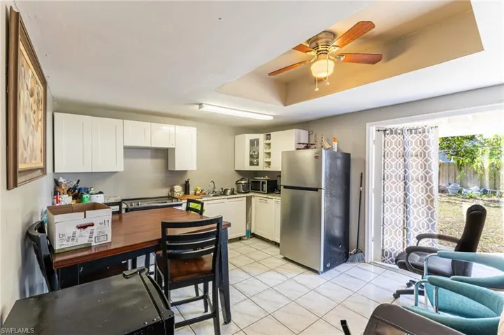 Kitchen featuring stainless steel appliances, light countertops, glass insert cabinets, light tile patterned flooring, and a sink