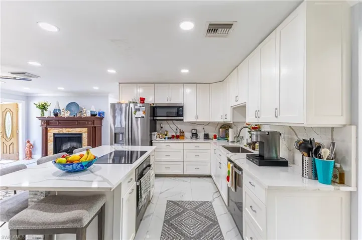 Kitchen with tasteful backsplash, visible vents, marble finish floor, stainless steel appliances, and a sink