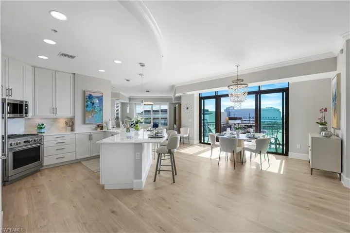 Kitchen featuring white cabinets, a kitchen bar, decorative light fixtures, tasteful backsplash, and appliances with stainless steel finishes