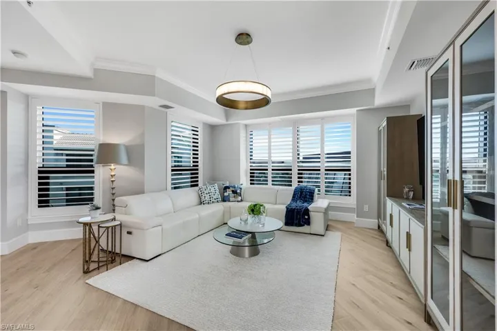 Living room with built in cabinets for storage and TV , crown molding, and plenty of natural light