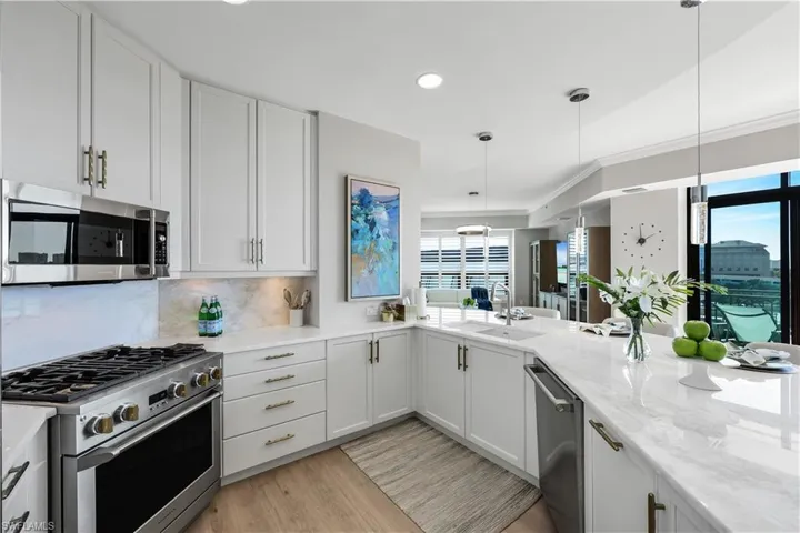 Kitchen featuring stainless steel appliances, decorative light fixtures, white cabinetry, light stone counters, and recessed lighting
