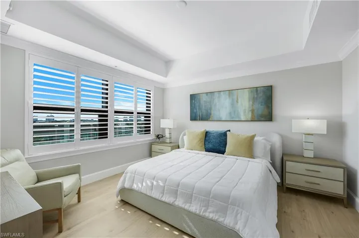 Primary Bedroom with a tray ceiling , plantation shutters and wood finished floors