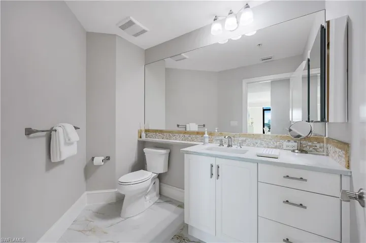 Updated Guest Bathroom with light marble finish flooring and vanity