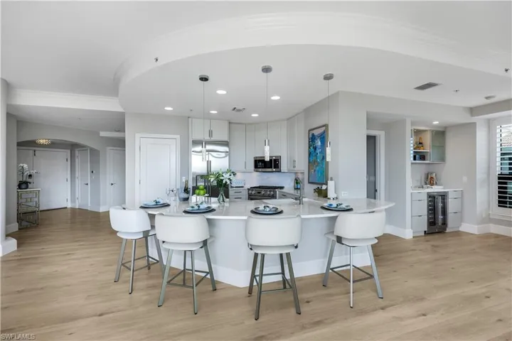 Kitchen featuring arched walkways, high end appliances, a kitchen bar, a peninsula, and hanging light fixtures