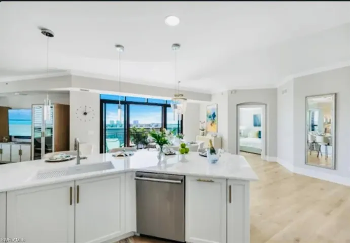 Open Majestic Kitchen featuring white cabinets, stainless steel dishwasher, hanging light fixtures, and light wood-style flooring