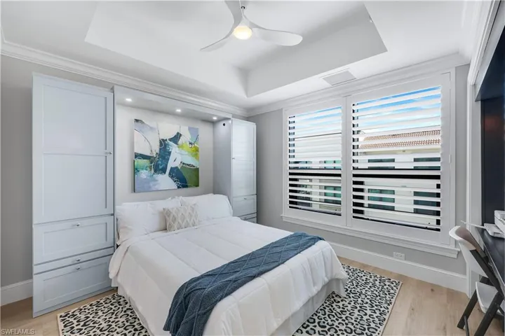 Second Bedroom featuring a raised ceiling, ceiling fan, light wood-style flooring and plantation shutters