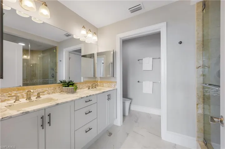 Updated Full bathroom featuring a stall shower, double vanity, and light marble finish flooring