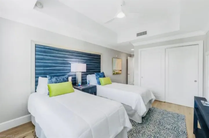 Guest Bedroom featuring light wood-style flooring, a closet, ceiling fan, and a raised ceiling
