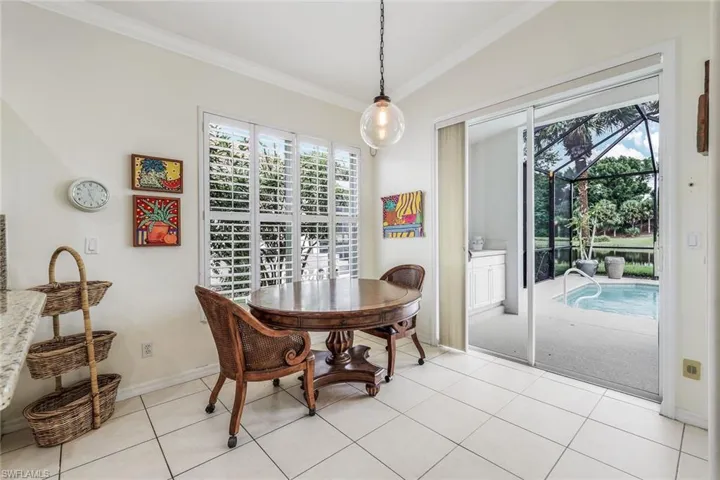 Tiled dining area featuring vaulted ceiling and ornamental molding