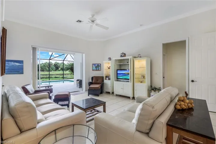 Tiled living room with ornamental molding and ceiling fan