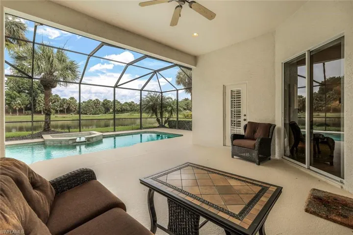 View of pool featuring an in ground hot tub, a patio, glass enclosure, and ceiling fan