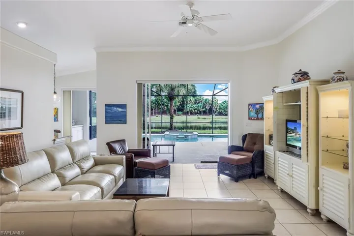 Living room with light tile flooring, crown molding, and ceiling fan