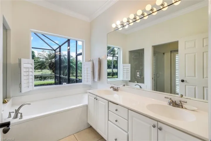 Master Bathroom with pool access featuring tile flooring, dual vanity, plus walk in shower, and crown molding