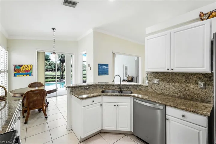 Kitchen featuring hanging light fixtures, sink, stainless steel dishwasher, and dark stone counters