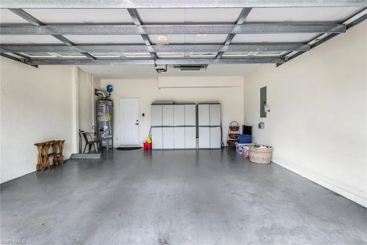 Garage featuring electric panel, gas water heater, and a garage door opener