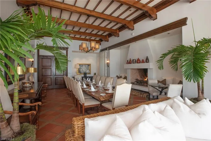 Library featuring vaulted ceiling with beams, a fireplace, a chandelier, and hardwood / wood-style flooring