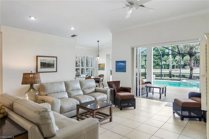Tiled living room featuring ceiling fan and ornamental molding