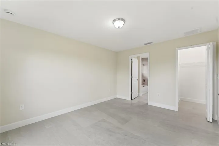 Unfurnished bedroom featuring a spacious closet and baseboards