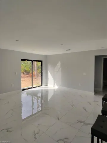 Spare room featuring light marble finish floors and baseboards