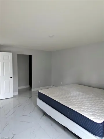 Bedroom featuring baseboards and light marble finish flooring