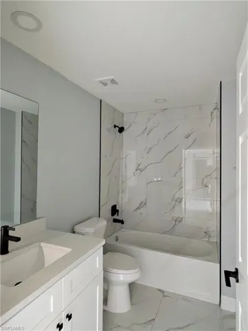 Full bathroom featuring vanity, bathing tub / shower combination, and light marble finish floors
