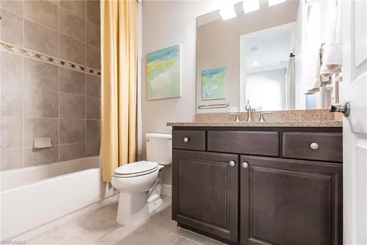 Bathroom featuring vanity, shower / bath combo with shower curtain, and light tile patterned floors