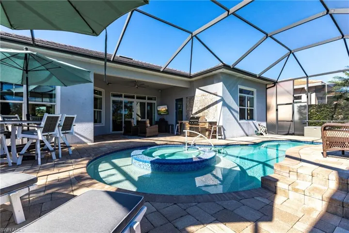 View of swimming pool with a sunroom, a patio area, a pool with connected hot tub, a ceiling fan, and glass enclosure
