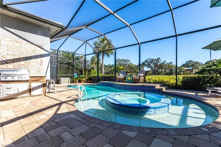 View of swimming pool featuring area for grilling, a patio, a pool with connected hot tub, a sunroom, and glass enclosure