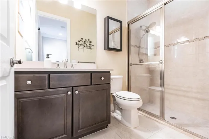 Bathroom featuring vanity, light tile patterned floors, and a stall shower