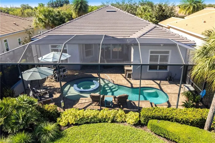 Rear view of house with a lanai, a sunroom, and a pool with connected hot tub