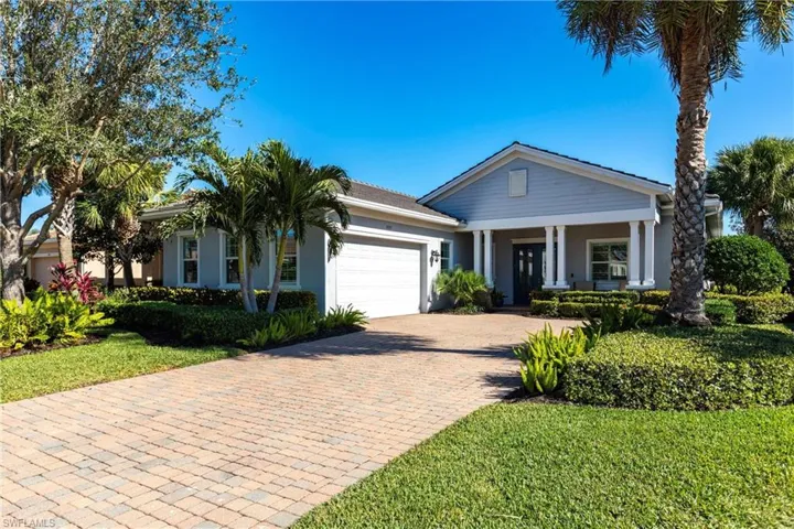 View of front facade with decorative driveway, an attached garage, stucco siding, a front lawn, and covered porch