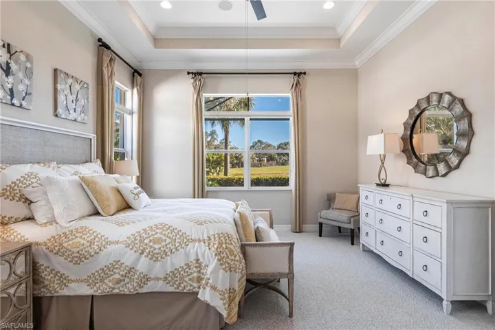 Bedroom featuring light colored carpet, ornamental molding, a raised ceiling, ceiling fan, and recessed lighting