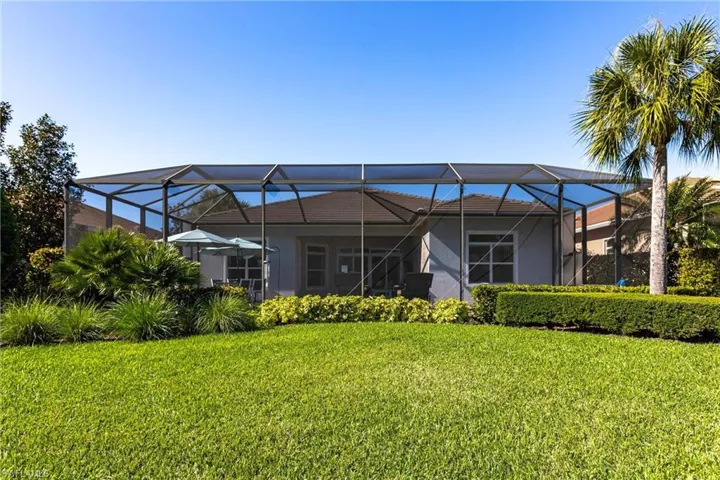 Back of house featuring a sunroom, glass enclosure, and a lawn