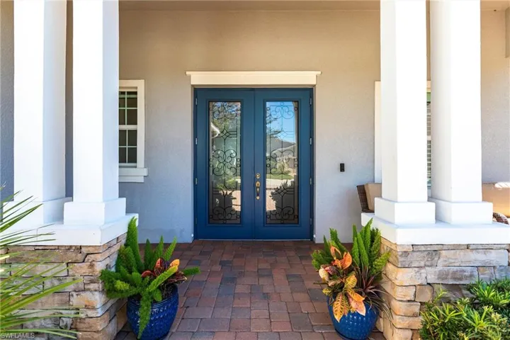View of exterior entry featuring french doors, covered porch, and stucco siding