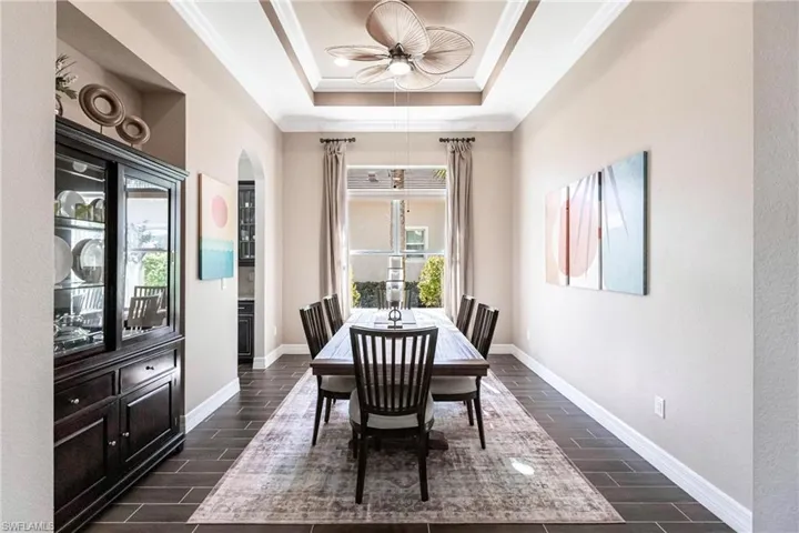 Dining space with wood finish floors, ornamental molding, ceiling fan, and a raised ceiling