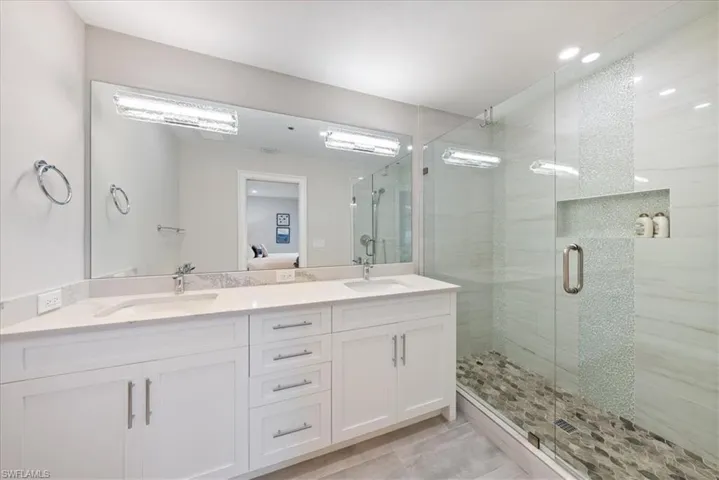 Bathroom with tile patterned floors, a shower with door, and dual bowl vanity