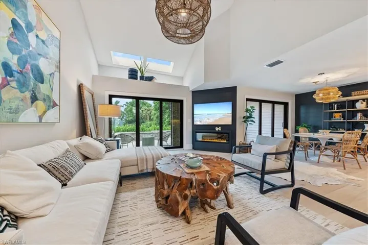 Living room with a skylight, high vaulted ceiling, and light hardwood / wood-style floors