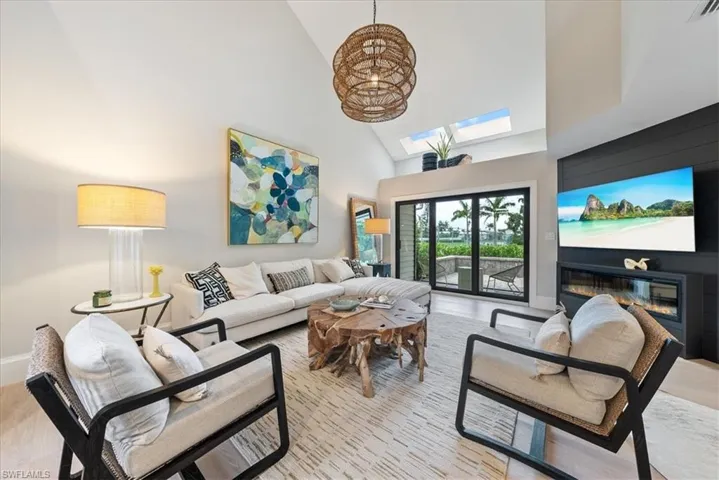 Living room featuring a skylight, light wood-type flooring, and high vaulted ceiling