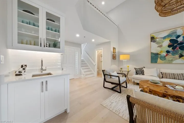Living room with light hardwood / wood-style floors, sink, and high vaulted ceiling