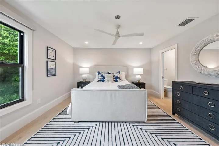 Bedroom with ceiling fan, ensuite bathroom, and light hardwood / wood-style flooring