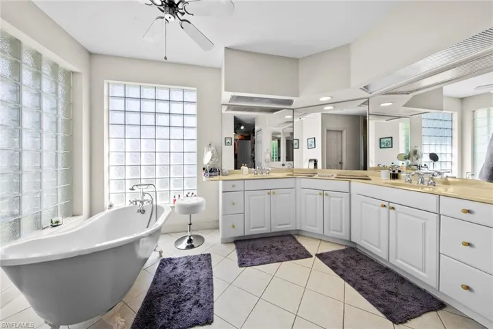 Bathroom with tile patterned flooring, a bath, vanity, and ceiling fan