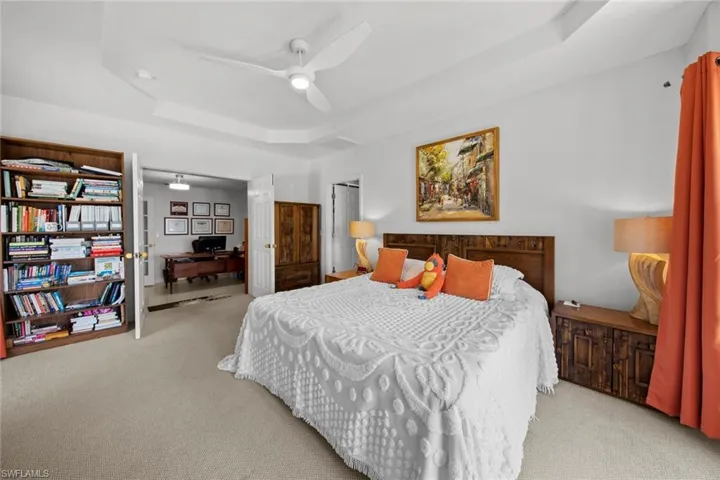 Bedroom featuring a tray ceiling, ceiling fan, and light colored carpet