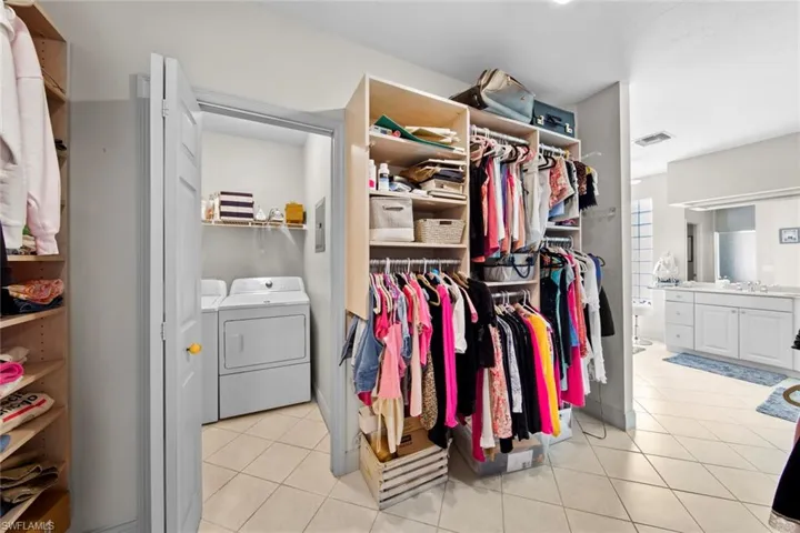 Spacious closet with sink, light tile patterned flooring, and washer and dryer
