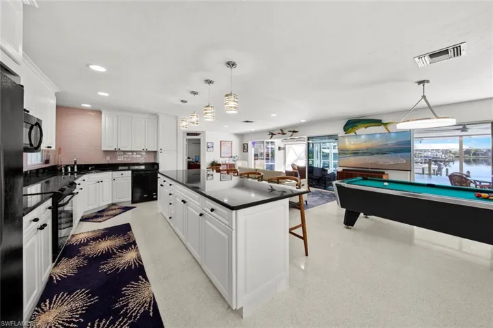 Kitchen with a breakfast bar area, white cabinetry, pendant lighting, and pool table