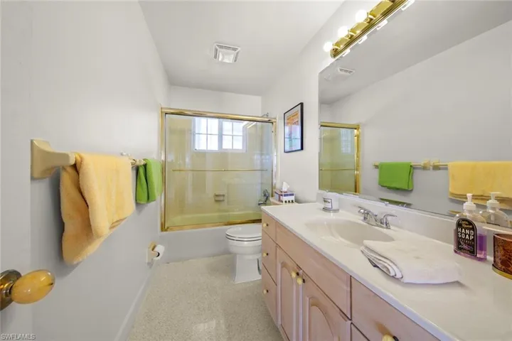 Full bathroom featuring vanity, toilet, and bath / shower combo with glass door